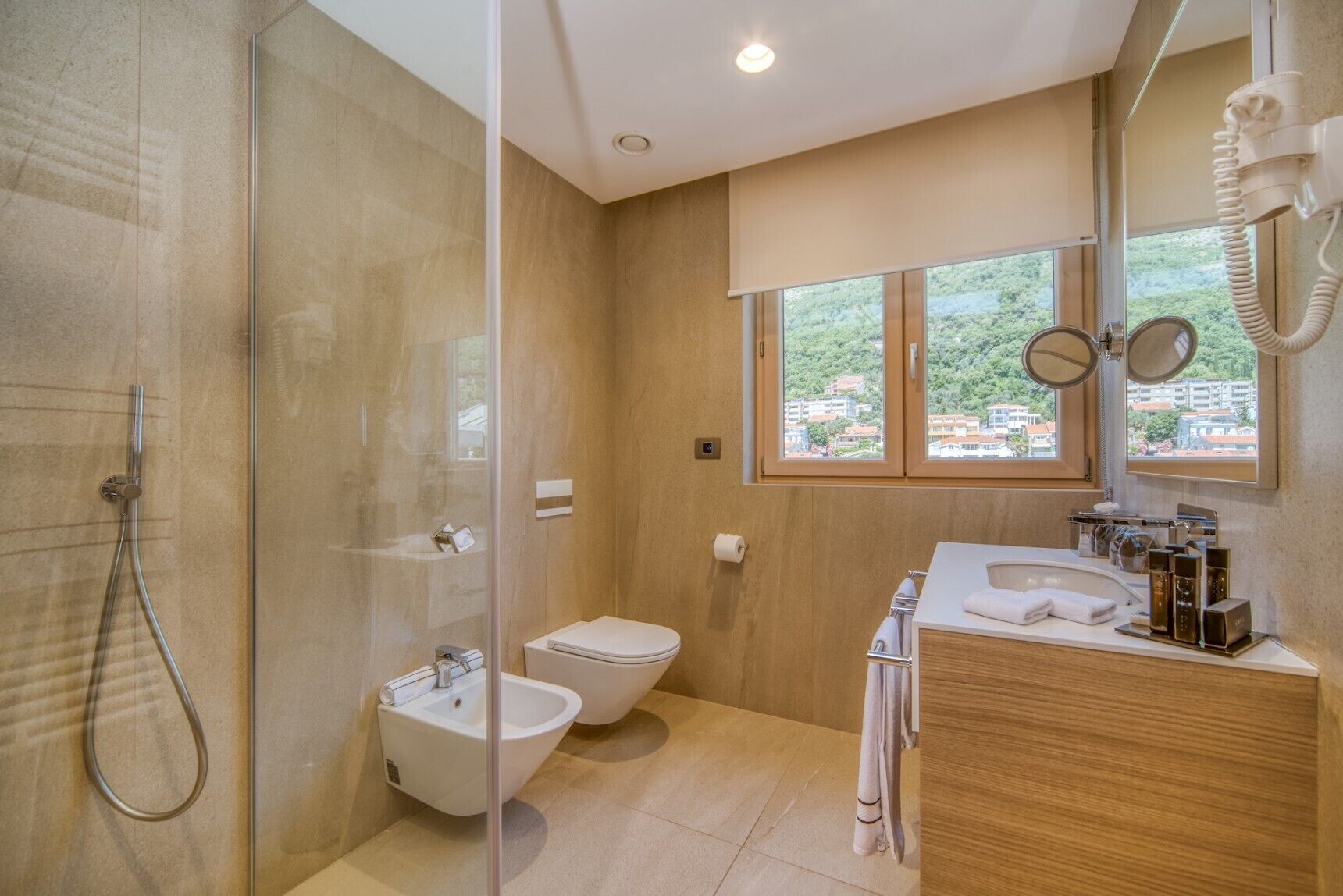 Un baño moderno con ducha de vidrio, un bidé, un inodoro y un lavabo con espejo.
