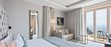 Una habitación de hotel con una cama grande, un sofá, una mesita y un balcón con vistas.
