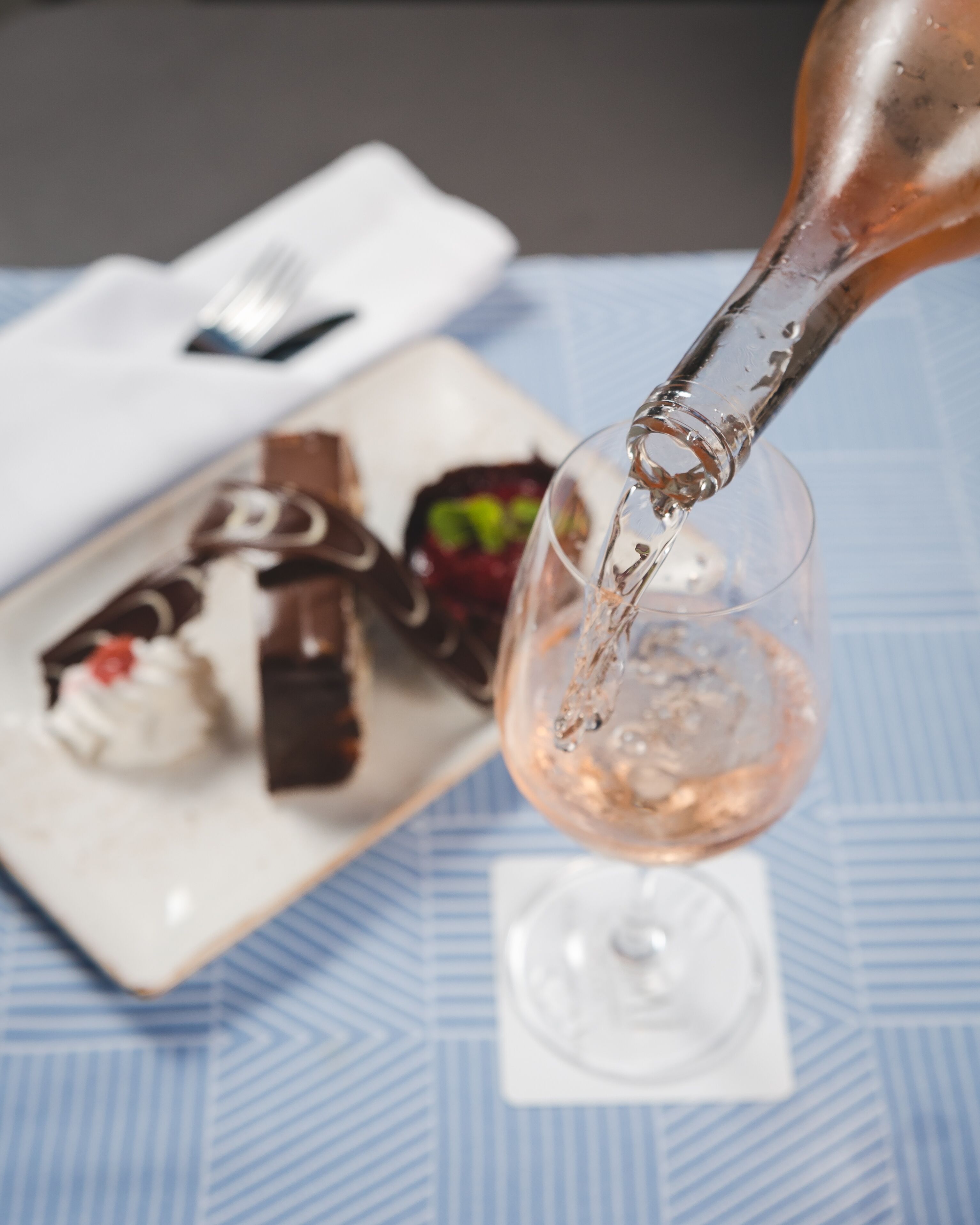 A glass of wine being poured onto a plate of assorted desserts.