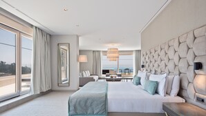 Una habitación de hotel moderna con una cama grande, vistas al mar y un balcón.