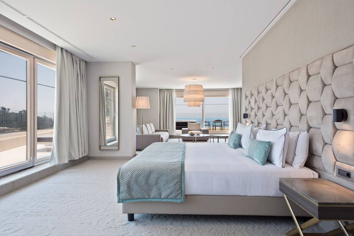 Una habitación de hotel moderna con una cama grande, vistas al mar y un balcón.