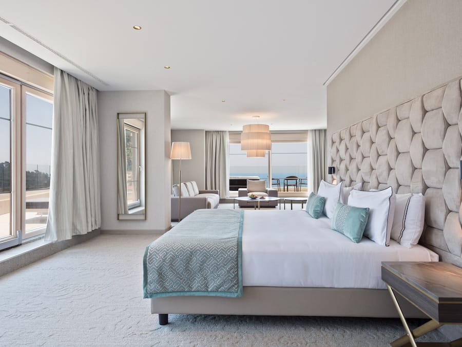 Een moderne hotelkamer met een groot bed, uitzicht op zee en een balkon.