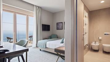 A hotel room with a bed, a desk, a chair, a TV, a window with a view, and a bathroom.
