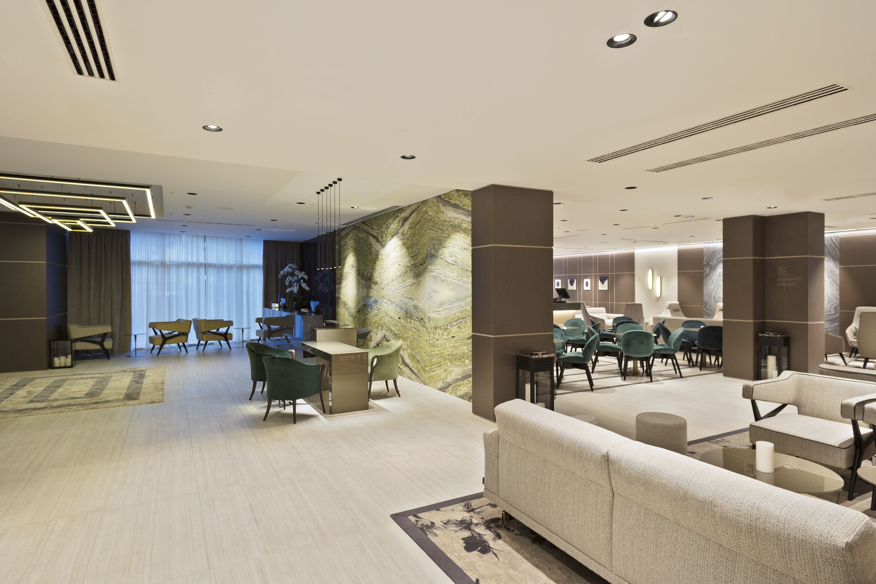 A modern lobby with a reception desk, seating area, and a large wall with a marble-like pattern.
