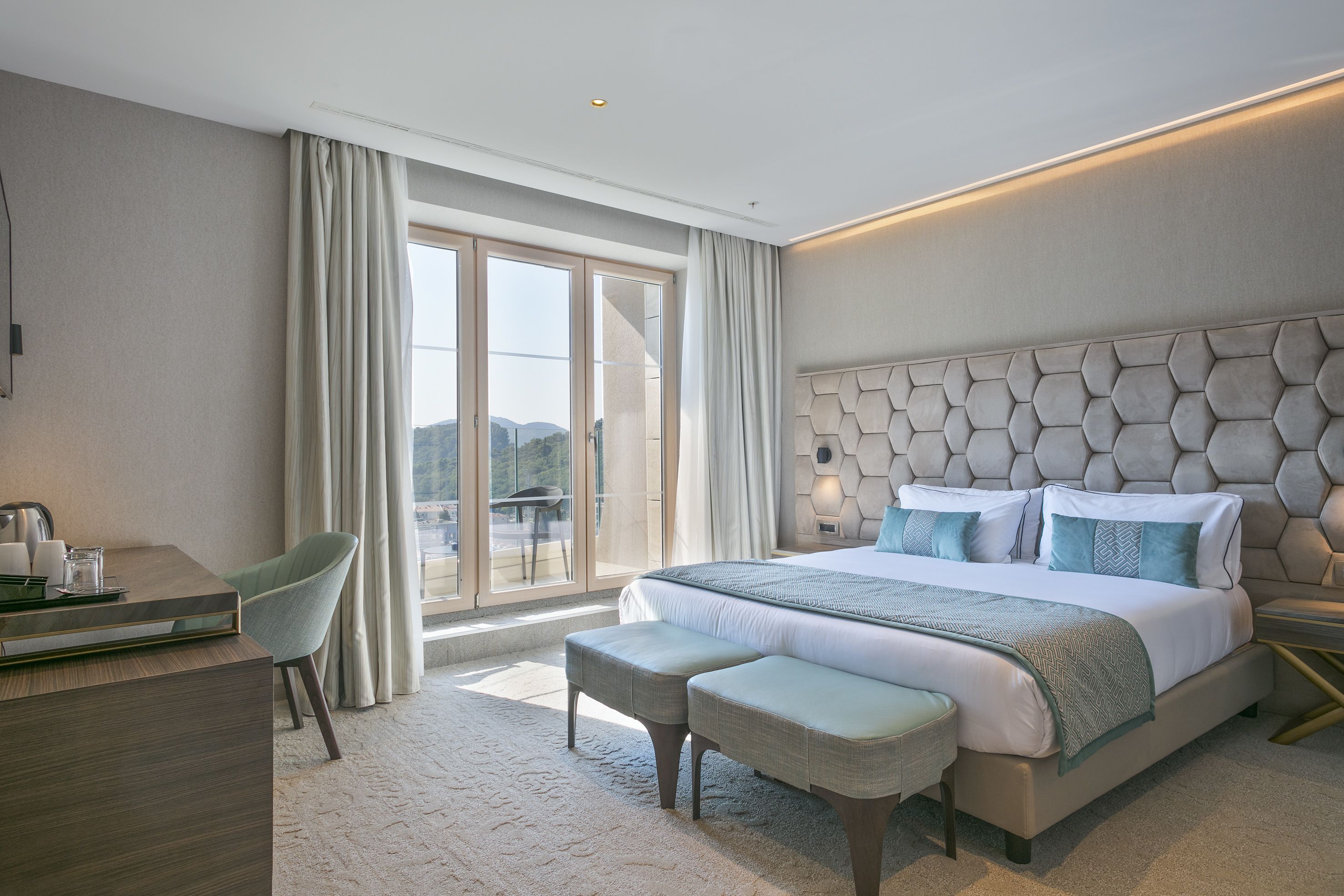 Et moderne hotelværelse med en stor seng, et skrivebord og udsigt til det fri.