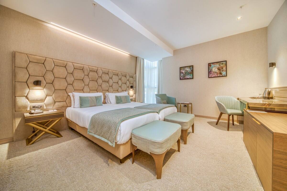 Una habitación de hotel moderna con una cama grande, mesitas de noche, un escritorio y una silla.