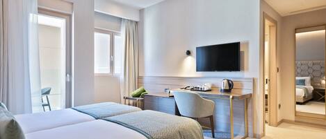A hotel room with a bed, desk, chair, TV, and a view of the outside.