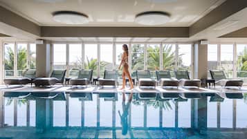 Una piscina techada, una piscina al aire libre, sombrillas