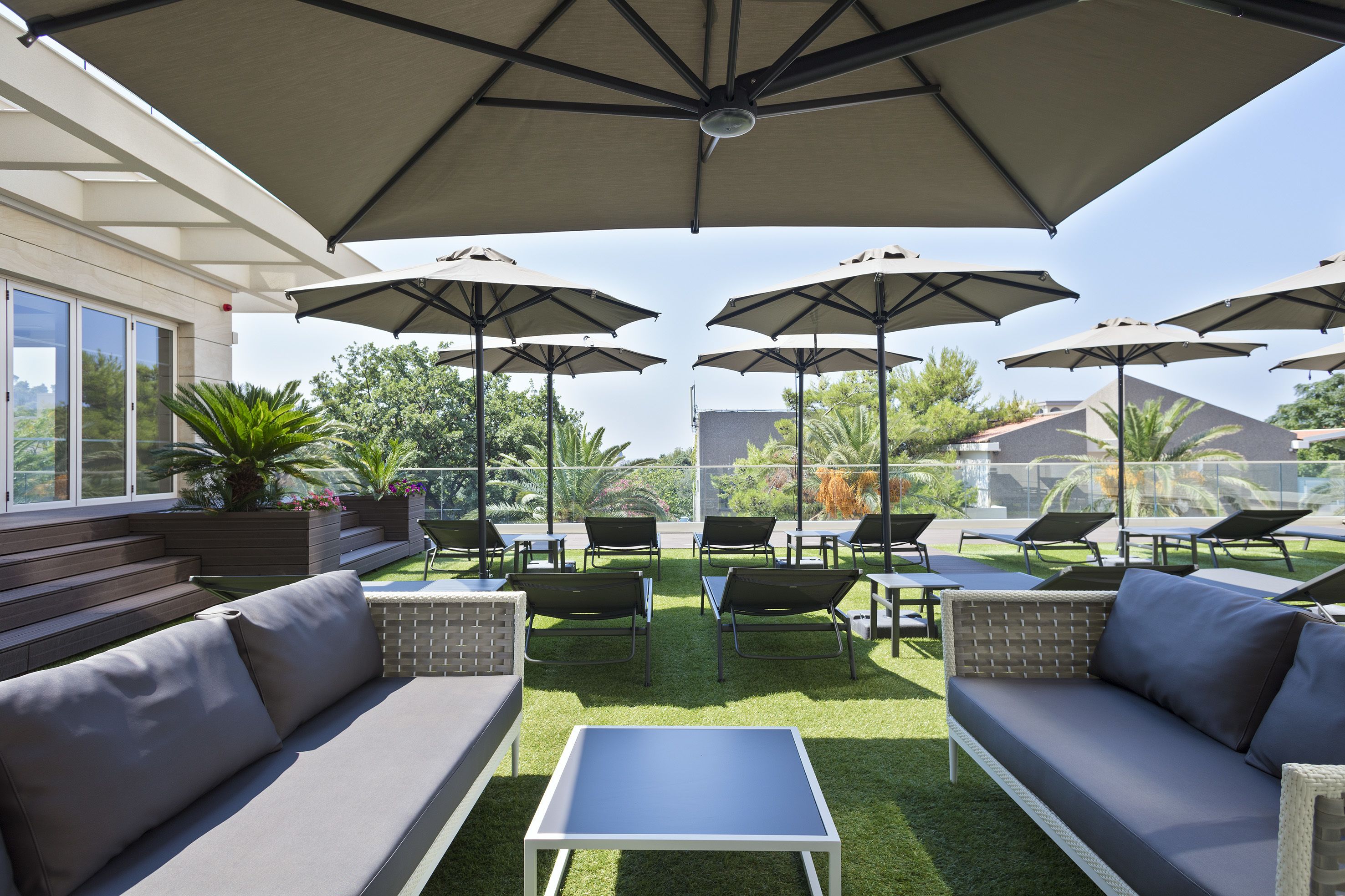An outdoor patio area with multiple seating options, including sofas and chairs, under large umbrellas.