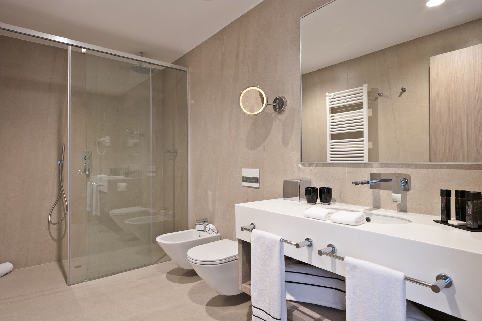 Un baño moderno con cabina de ducha de vidrio, inodoro blanco y tocador doble.