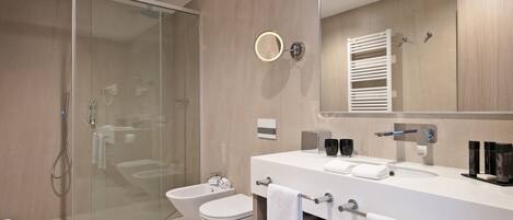 Un baño moderno con cabina de ducha de vidrio, inodoro blanco y tocador doble.