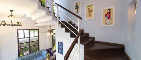 Un interior moderno con una escalera, un sofá y obras de arte en las paredes.