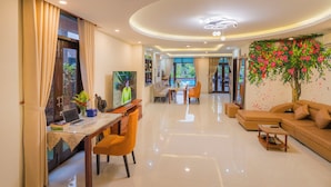 A spacious living area with a dining table, sofas, a TV, and a ceiling fan. - VIP Garden Villa and Pool (Da Nang)