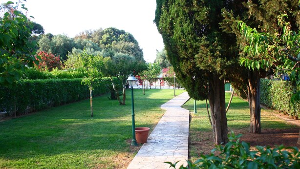 A stone pathway in a well-maintained garden with trimmed hedges and trees. - B&B Verdegiada (Brindisi)
