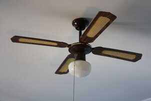 Un ventilador de techo con cuatro aspas y una lámpara central.