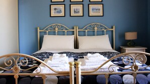 A bed with a metal frame, white pillows, and a blue wall with framed pictures. - B&B Verdegiada (Brindisi)
