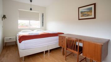 A bedroom with a bed, a desk, and a chair.