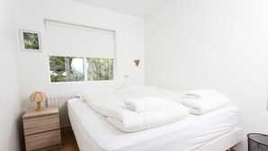 Een slaapkamer met een bed, nachtkastje, raam en radiator.