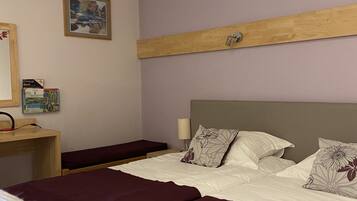 Habitación de hotel con una cama grande, un cabecero de madera, un escritorio con lámpara y un cuadro en la pared.