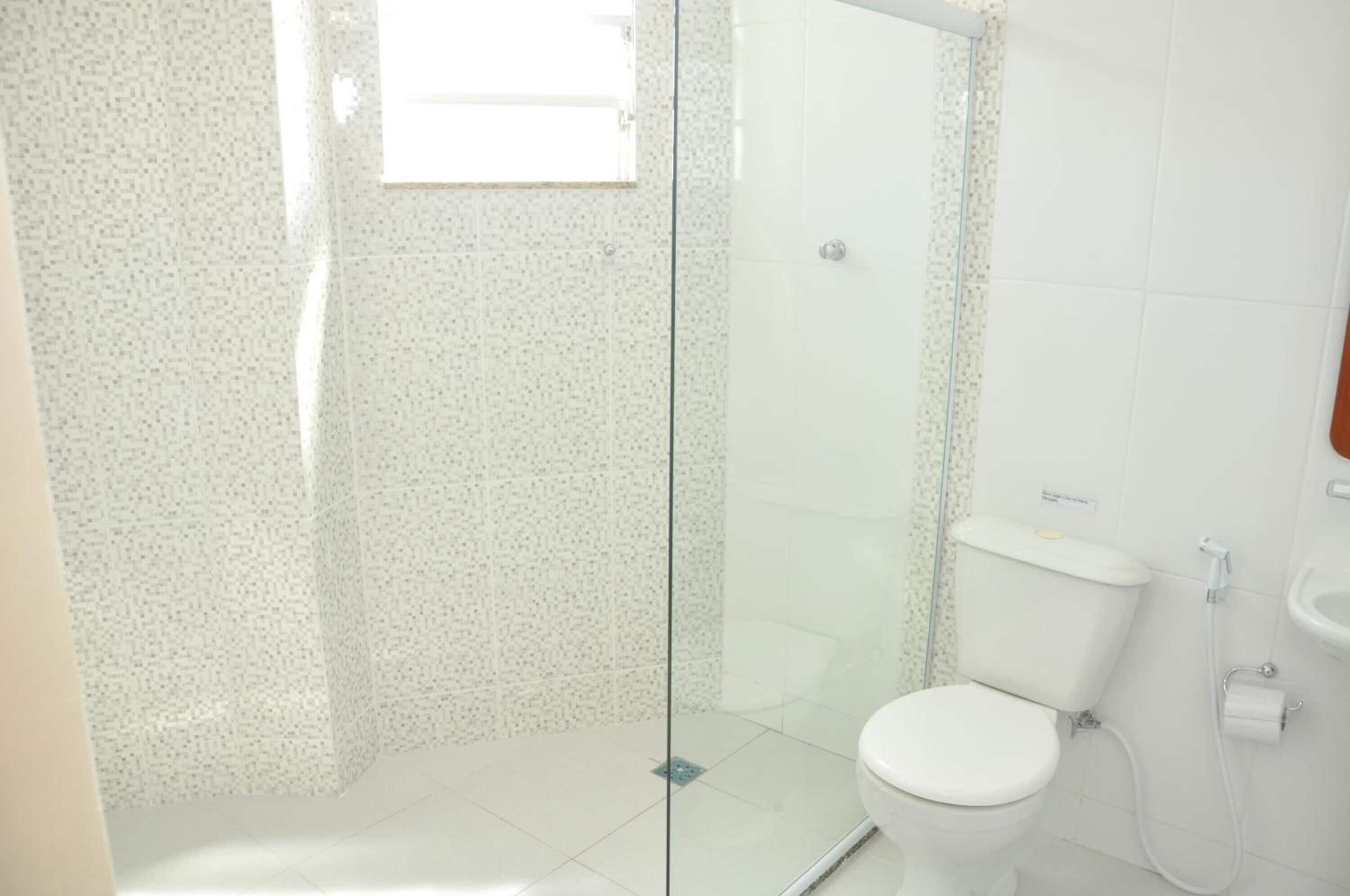 A bathroom with a glass shower enclosure, a toilet, and a sink.
