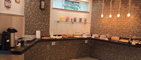 A breakfast bar with various food items and a coffee station.