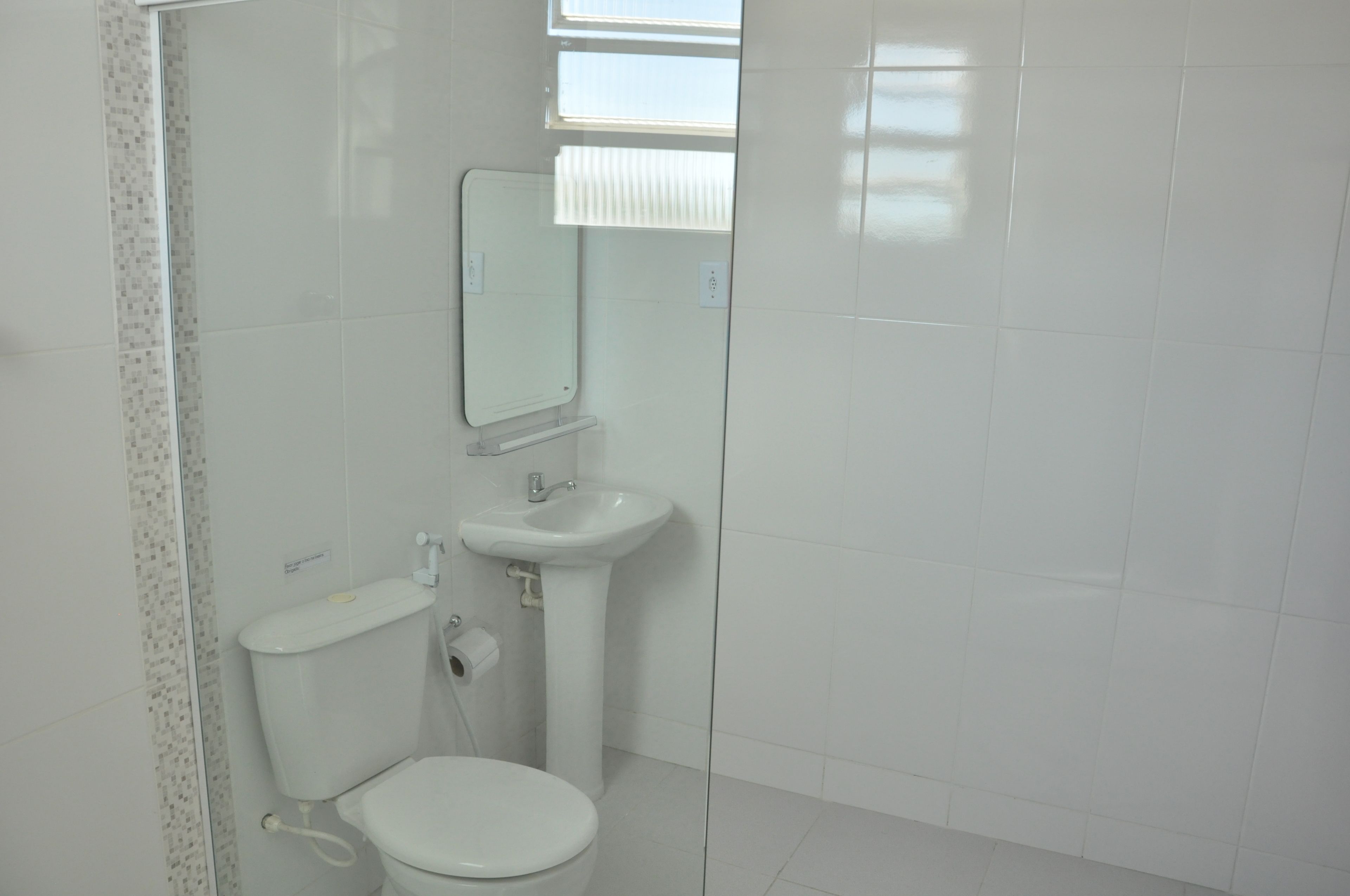 A bathroom with a toilet, sink, and mirror.