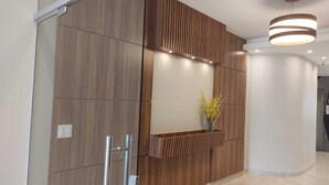 A modern reception area with wooden paneling, a glass partition, and a vase with yellow flowers. - Hotel Pousada Figueiredo (Araruama)