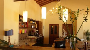 A bar area with a counter, shelves with bottles, and a decorative plant. - Agriturismo La Regina (Cascina)