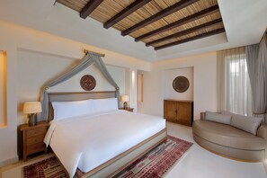 A spacious bedroom with a large bed, a sofa, and a ceiling with wooden beams.