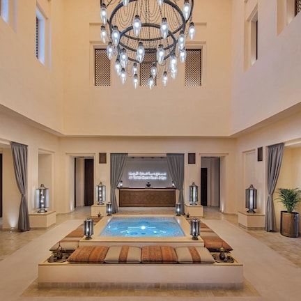 A spacious lobby with a large central pool, elegant chandeliers, and a reception desk.