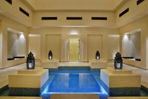 A hotel lobby with a central pool, two side mirrors, and a door at the end.