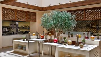 Une cuisine moderne dotée d’appareils électroménagers intégrés, d’un îlot central agrémenté d’un arbre et de pots décoratifs.