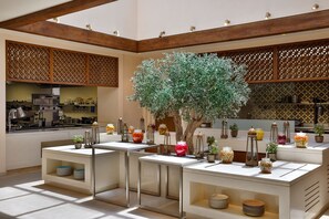 A modern kitchen with built-in appliances, a central island with a tree, and decorative jars.