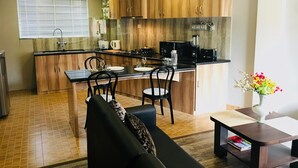 Uma cozinha compacta com armários de madeira, bancada preta e uma área de refeições com sofá e mesa.