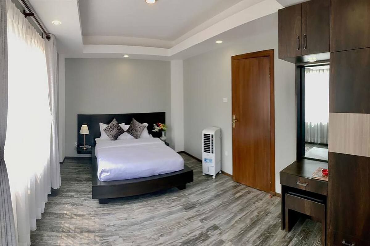 A modern bedroom with a bed, bedside table, lamp, and a wardrobe.