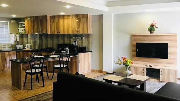 Uma cozinha moderna com armários de madeira, uma ilha central com assentos, fogão embutido e uma TV de tela plana na parede.
