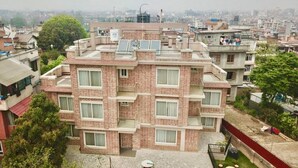 Um edifício residencial de vários andares com fachada de tijolos, múltiplas varandas e painéis solares no telhado.