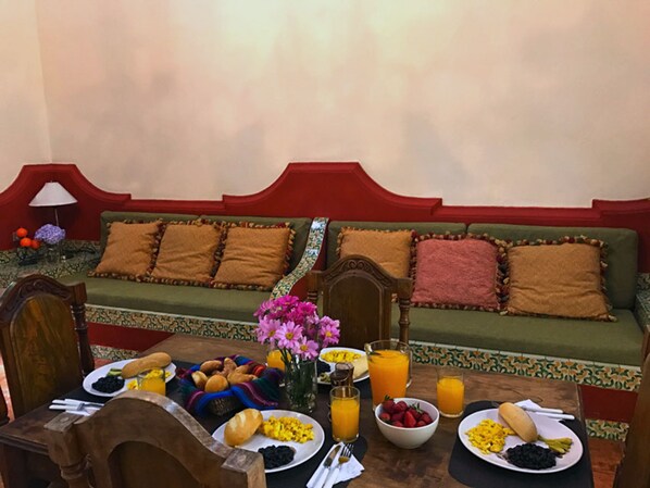 A breakfast setup with a table, plates of food, and a sofa in the background.