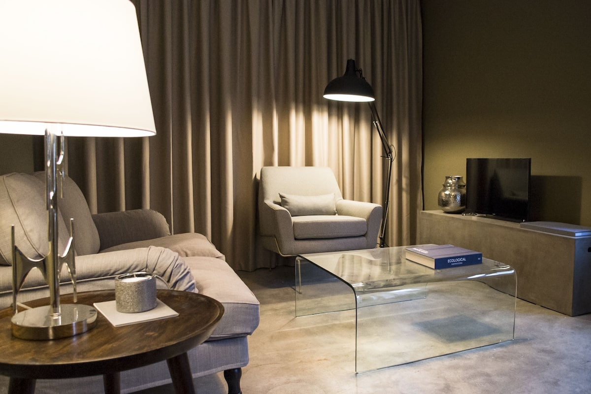 A modern living room with a sofa, armchair, and glass coffee table.