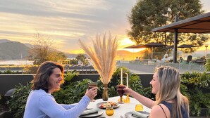 A dining table set outdoors with a view of the sunset and hills in the background. - Cinco Rodavento (Valle de Bravo)