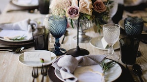 A table set for a meal with a name card, cutlery, plates, glasses, and a centerpiece with flowers and candles. - Cinco Rodavento (Valle de Bravo)