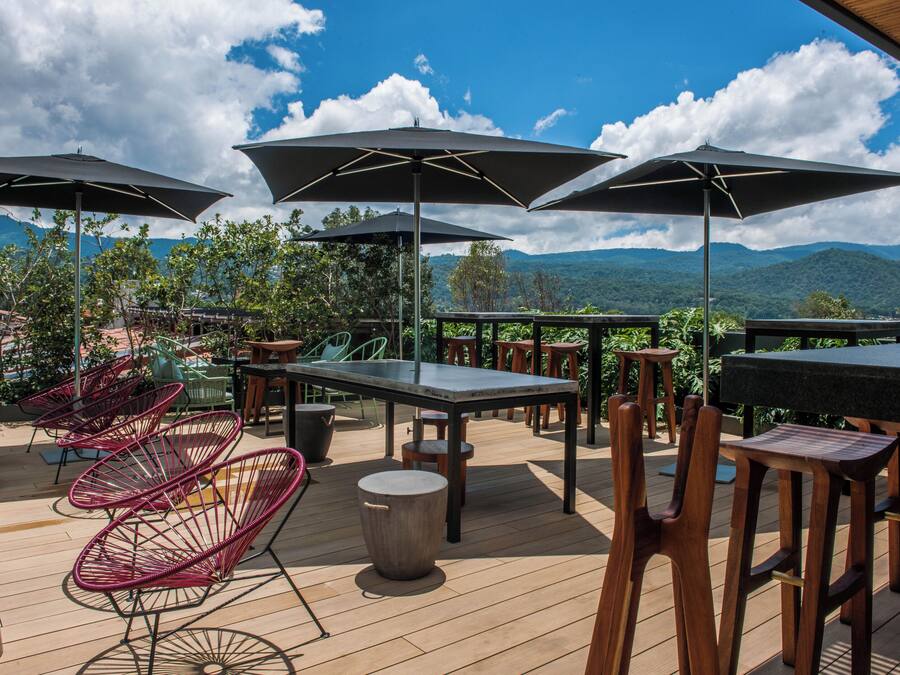 Une terrasse extérieure avec des tables et des chaises, des parasols et une vue sur les montagnes.