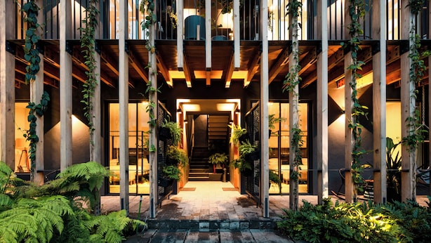 A building entrance with a wooden facade, vertical supports, and potted plants. - Cinco Rodavento (Valle de Bravo)