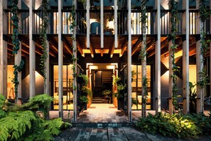 A building entrance with a wooden facade, vertical supports, and potted plants. - Cinco Rodavento (Valle de Bravo)