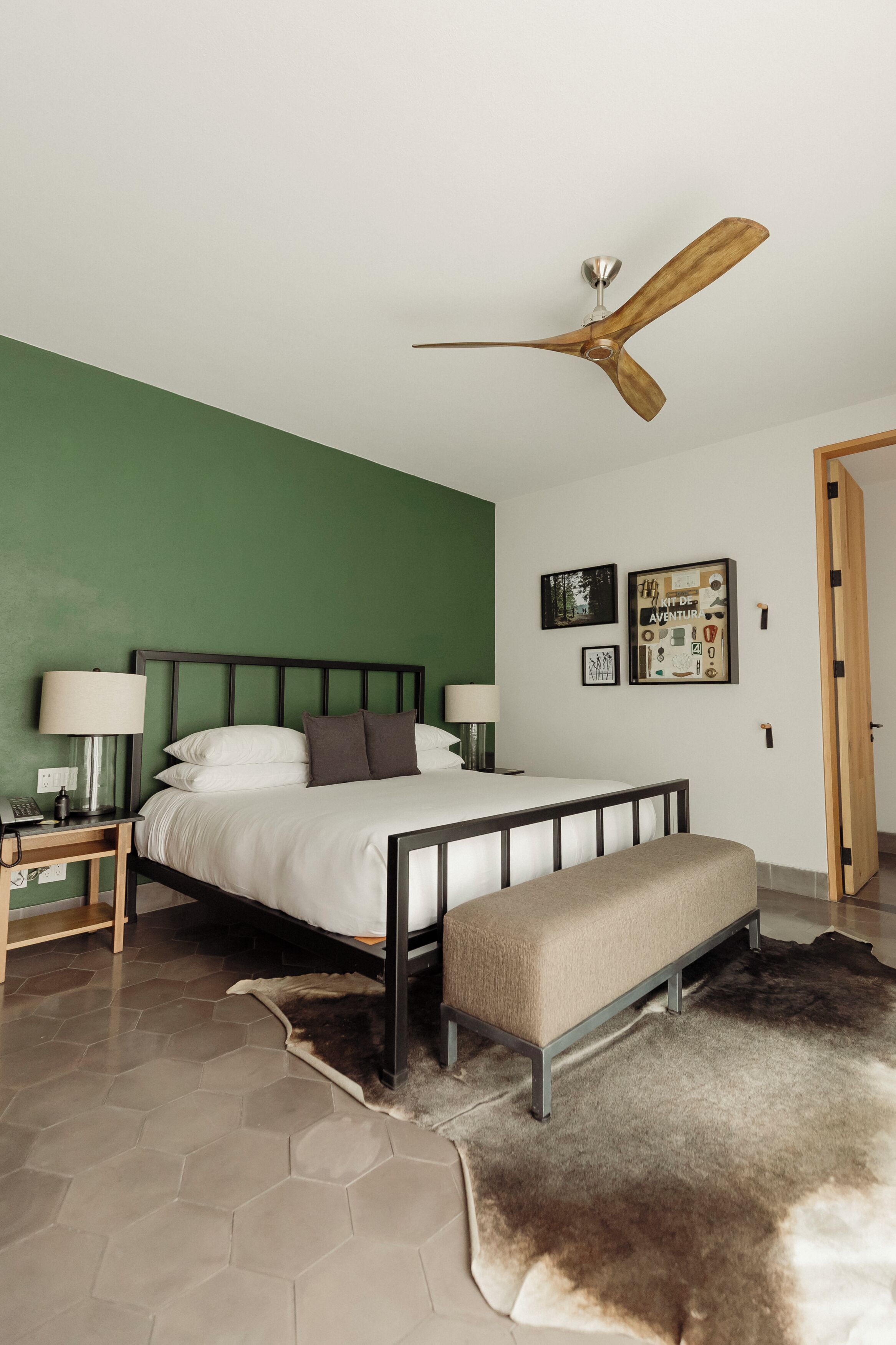 A bedroom with a bed, bedside tables, a ceiling fan, a bench, and a rug.
