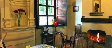 Un comedor con chimenea, muebles de madera y una mesa dispuesta para el desayuno.