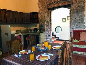 A dining area with a stone archway, wooden furniture, and breakfast items on the table. - Casita Santa Rosa (Antigua Guatemala)