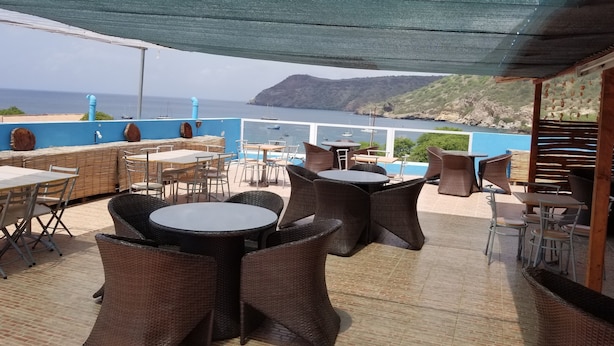 An outdoor seating area with wicker furniture and a view of the sea. - Hotel Cachoeira Tarrafal (Tarrafal)
