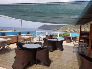 Un área de estar al aire libre con mobiliario de mimbre y vista al mar.