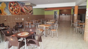 A restaurant with multiple tables and chairs, a tiled floor, and a mural on the wall depicting food. - Hotel Cachoeira Tarrafal (Tarrafal)